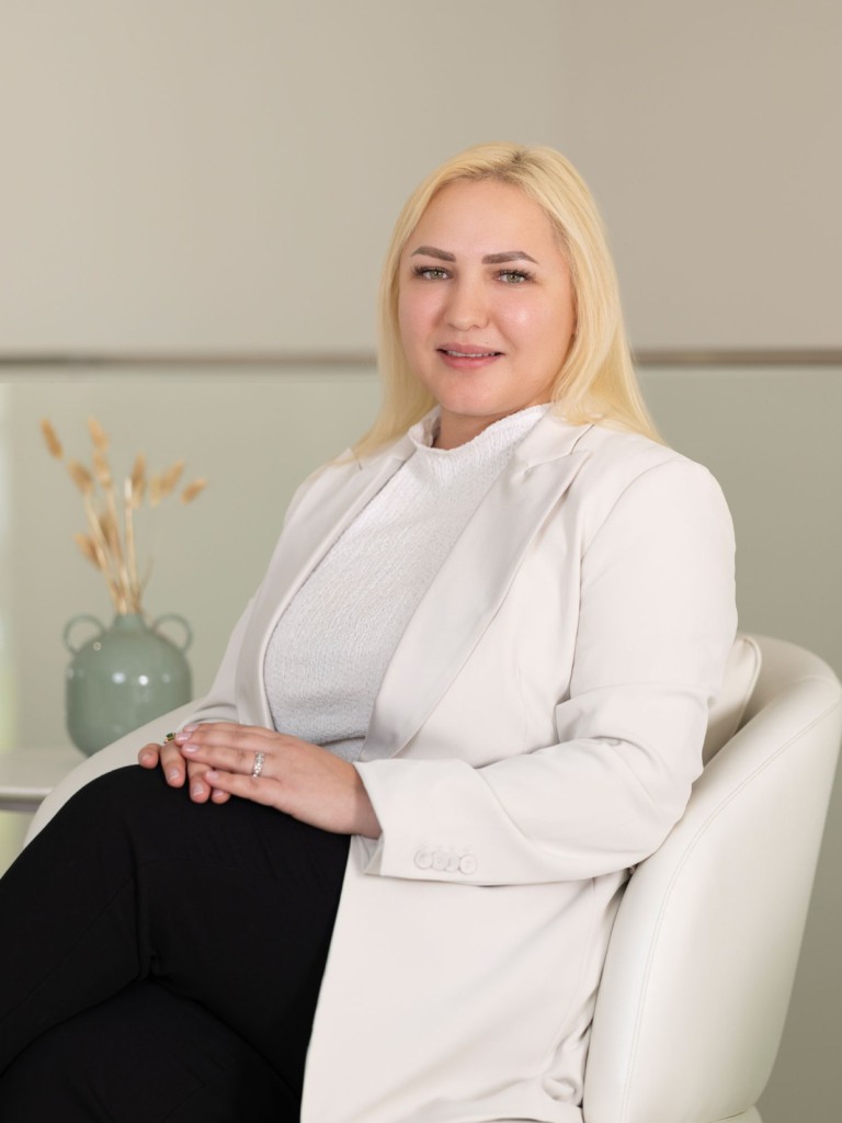 Ms. Olena Bondareva, Skin Care Specialist, posing in a clinic setting in a stylish white outfit.