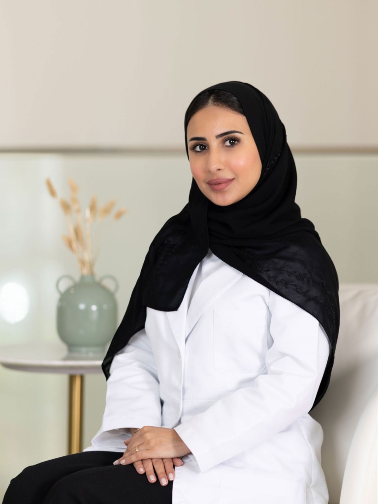 Ms. Heyam Esmail, Advanced Aesthetician and Skin Care Educator, seated in a clinic wearing a professional uniform.